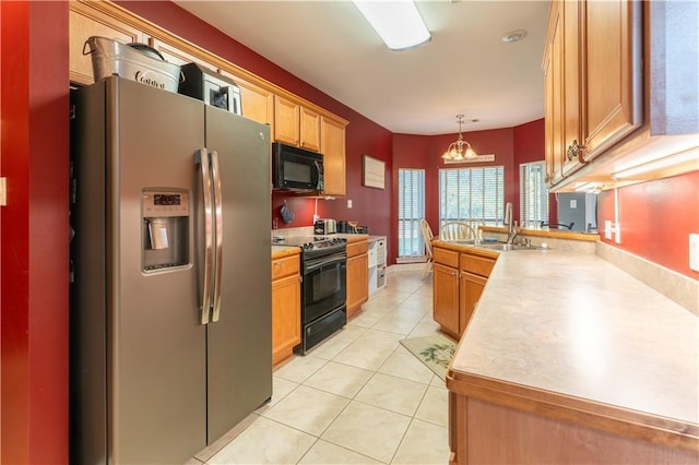 kitchen featuring light countertops, a peninsula, light tile patterned flooring, black appliances, and a sink