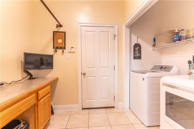 clothes washing area with washing machine and clothes dryer, light tile patterned floors, laundry area, and baseboards