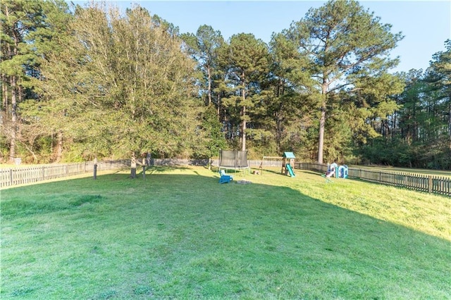 view of yard featuring a fenced backyard, a playground, and a trampoline