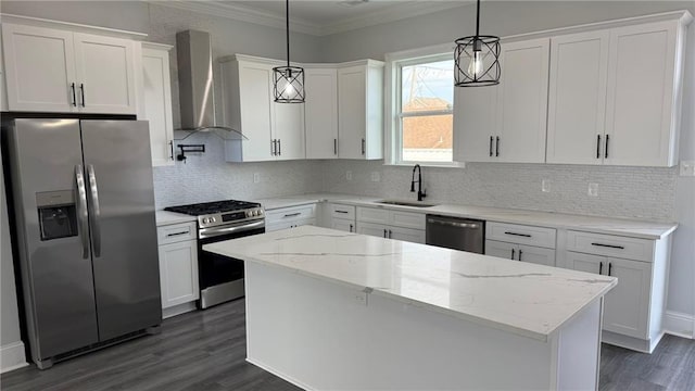 kitchen featuring ornamental molding, a sink, a kitchen island, stainless steel appliances, and wall chimney range hood