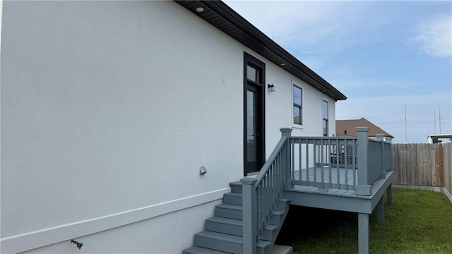 view of home's exterior featuring stucco siding, a wooden deck, and fence