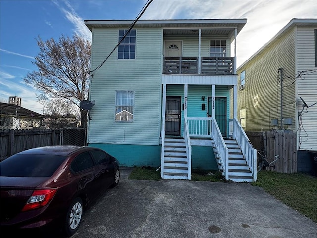 view of front of property featuring a balcony, covered porch, stairs, and fence