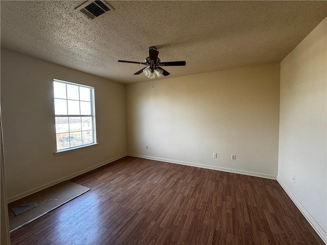 spare room with dark wood-type flooring, baseboards, visible vents, and ceiling fan