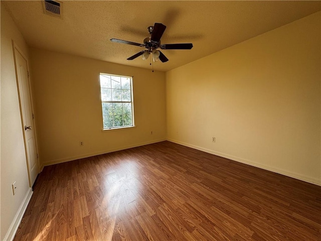 unfurnished room with visible vents, baseboards, and dark wood-type flooring