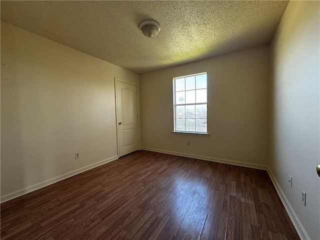 spare room featuring wood finished floors, baseboards, and a textured ceiling