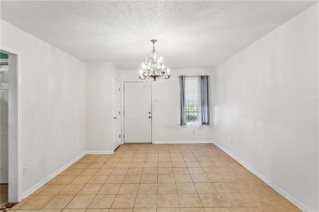 interior space with light tile patterned floors, a notable chandelier, a textured ceiling, and baseboards