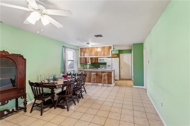 dining space featuring light tile patterned floors, visible vents, ceiling fan, and baseboards