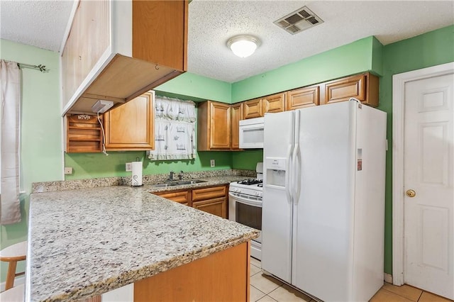 kitchen featuring white appliances, light tile patterned floors, a peninsula, and visible vents