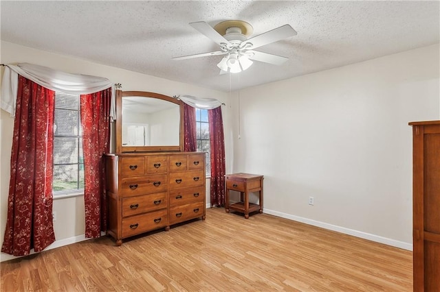 bedroom with light wood-style flooring, a ceiling fan, baseboards, and a textured ceiling