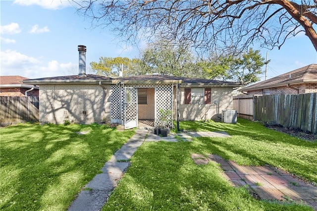 back of house with brick siding, central AC unit, a fenced backyard, and a lawn