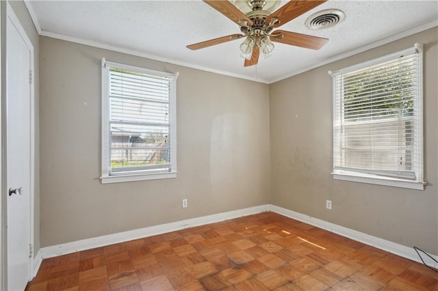 empty room featuring a wealth of natural light, visible vents, a ceiling fan, and baseboards