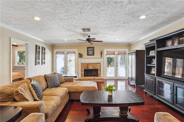 living room featuring a wealth of natural light, visible vents, a brick fireplace, and dark wood-style floors