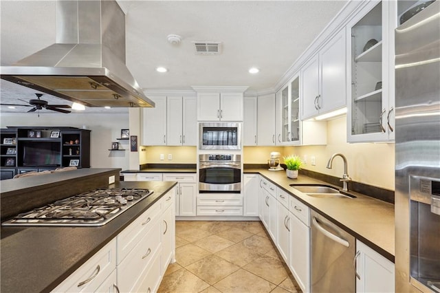 kitchen featuring visible vents, appliances with stainless steel finishes, island exhaust hood, white cabinets, and a sink