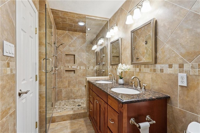 bathroom featuring a sink, tile walls, a stall shower, and double vanity