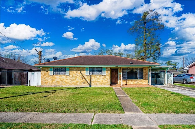 single story home featuring a front yard, fence, driveway, a carport, and brick siding