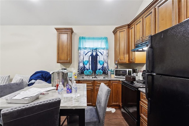 kitchen featuring brown cabinets, black appliances, a sink, under cabinet range hood, and dark wood finished floors