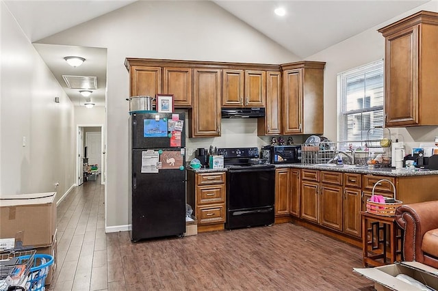 kitchen with under cabinet range hood, brown cabinets, and black appliances