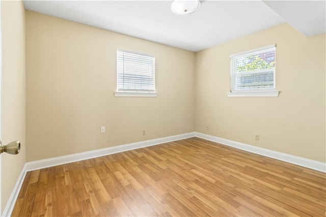 empty room with light wood finished floors, a healthy amount of sunlight, and baseboards