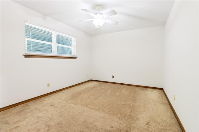 spare room with light carpet, a ceiling fan, and baseboards