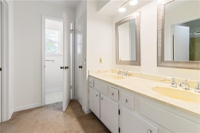 bathroom with double vanity, baseboards, and a sink