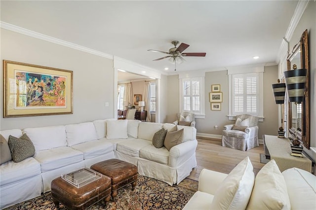 living area with a ceiling fan, crown molding, wood finished floors, and baseboards