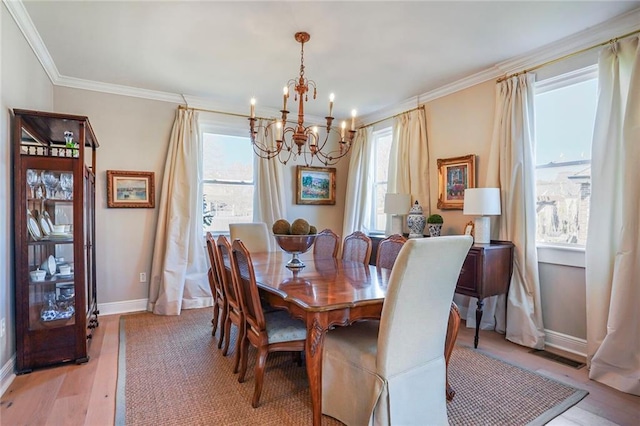 dining room with light wood finished floors, an inviting chandelier, crown molding, and baseboards