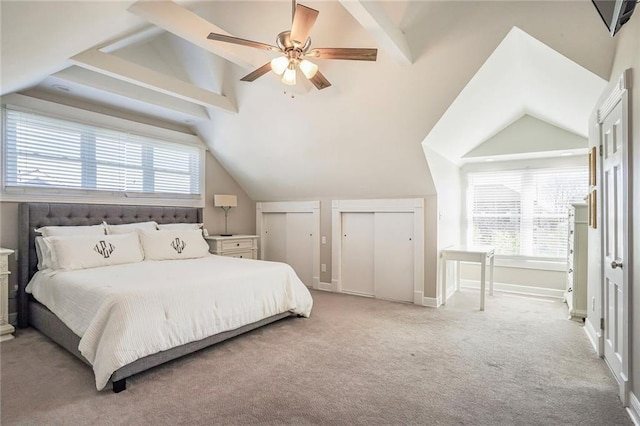 carpeted bedroom featuring ceiling fan, baseboards, lofted ceiling with beams, and multiple closets