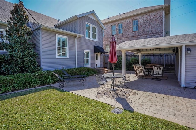 back of house with a patio, a yard, fence, and a shingled roof