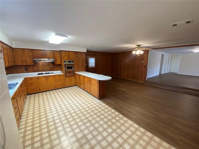 kitchen with light floors, visible vents, under cabinet range hood, stovetop, and light countertops