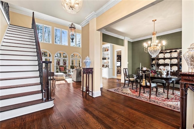 entryway with ornamental molding, dark wood-style floors, stairway, baseboards, and a chandelier