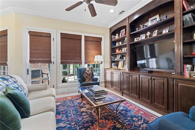 living room with visible vents, crown molding, a ceiling fan, and built in features