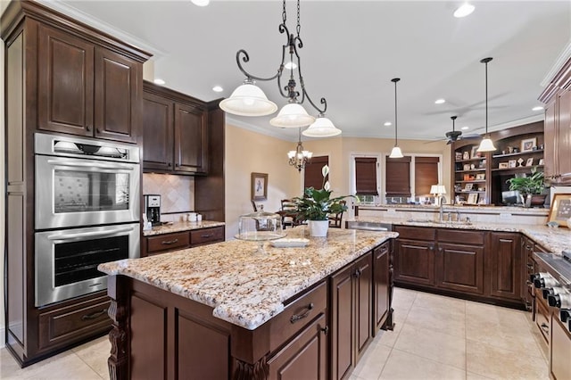 kitchen featuring dark brown cabinets, a kitchen island, ornamental molding, stainless steel double oven, and a sink