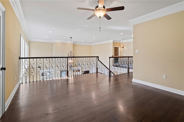 spare room featuring ceiling fan with notable chandelier, crown molding, wood finished floors, and baseboards