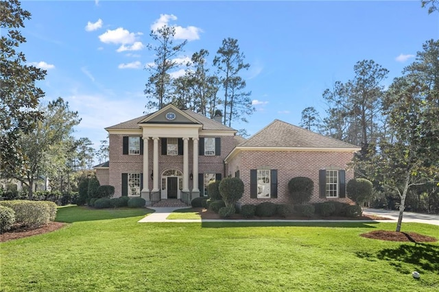 neoclassical home featuring a front lawn and brick siding