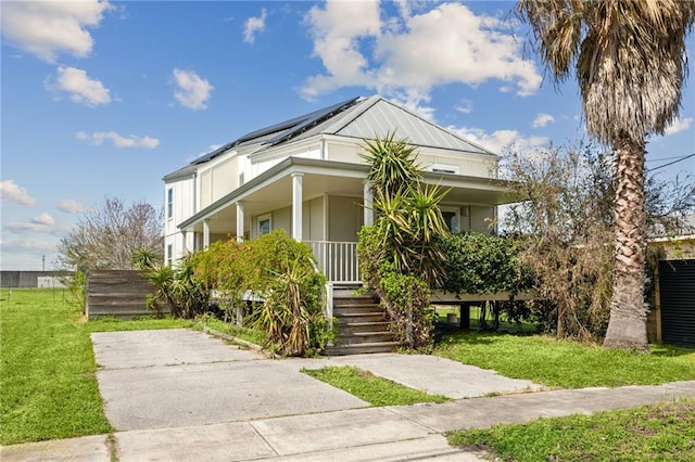 view of front of house featuring roof mounted solar panels, covered porch, and a front lawn