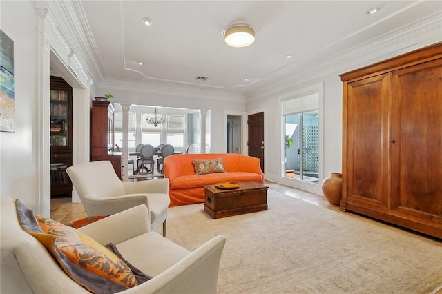 living area with a chandelier, crown molding, and decorative columns