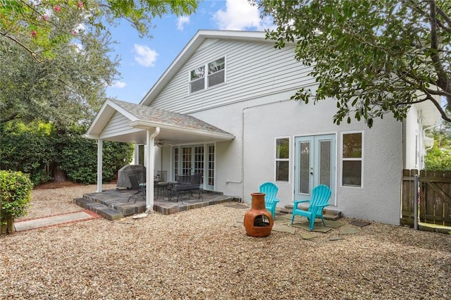 back of house featuring fence, roof with shingles, stucco siding, french doors, and a patio