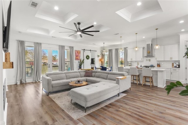 living room with visible vents, a barn door, recessed lighting, light wood-style flooring, and french doors