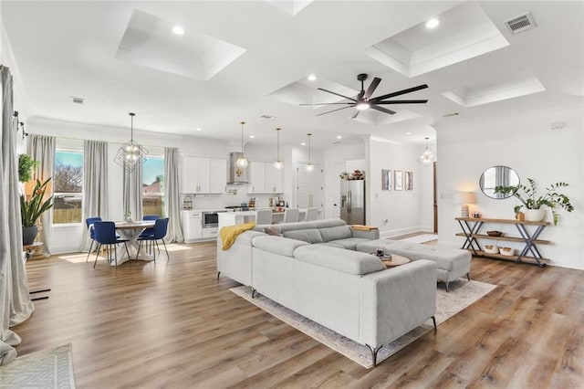 living room featuring light wood finished floors, visible vents, ceiling fan with notable chandelier, and recessed lighting