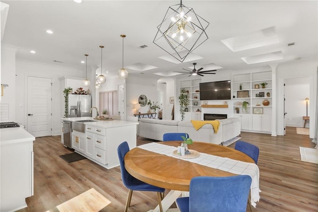 dining space featuring a ceiling fan, recessed lighting, a fireplace, and light wood-style floors