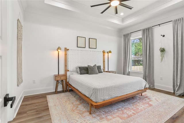 bedroom with recessed lighting, a raised ceiling, baseboards, and wood finished floors