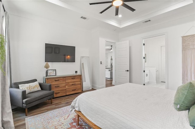 bedroom featuring visible vents, recessed lighting, a tray ceiling, and wood finished floors