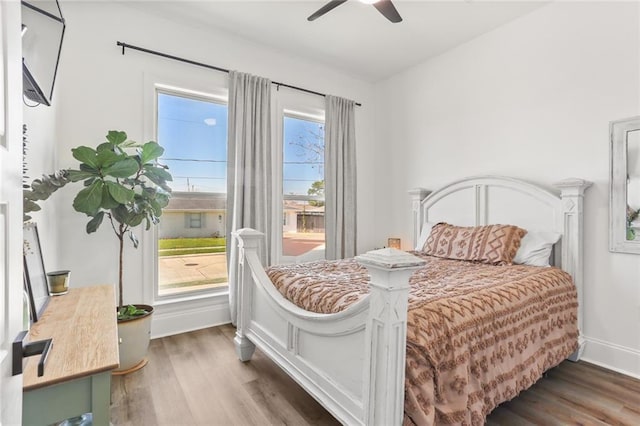 bedroom featuring multiple windows, wood finished floors, and baseboards