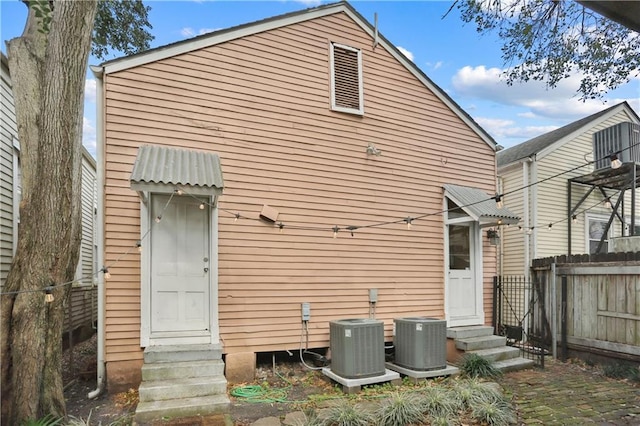 back of house featuring central air condition unit, fence, and entry steps