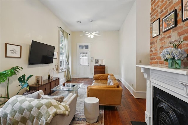 living room featuring visible vents, baseboards, dark wood finished floors, a fireplace, and ceiling fan