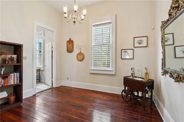 interior space featuring hardwood / wood-style floors, an inviting chandelier, and baseboards