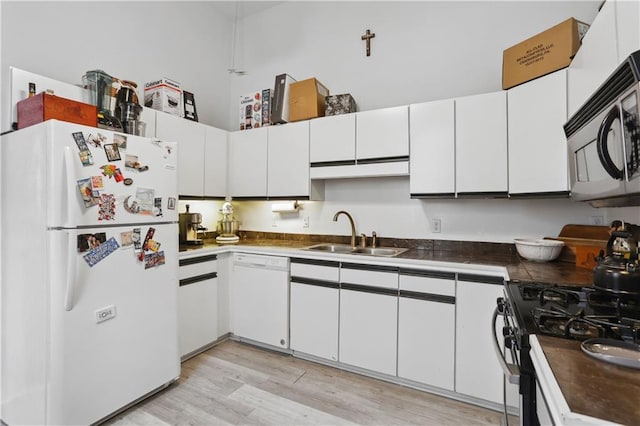 kitchen with light wood finished floors, white appliances, white cabinetry, and a sink