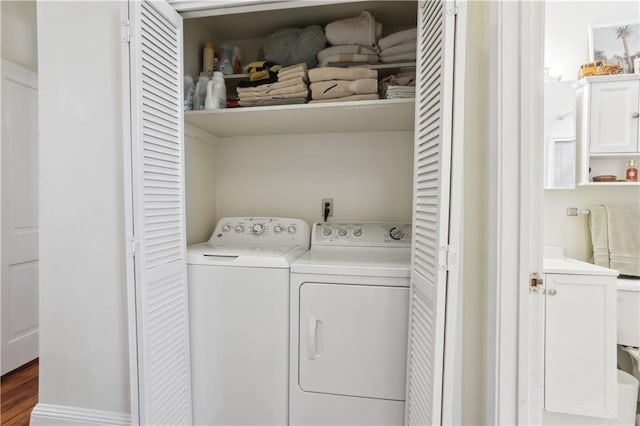 clothes washing area featuring wood finished floors, laundry area, and washer and clothes dryer