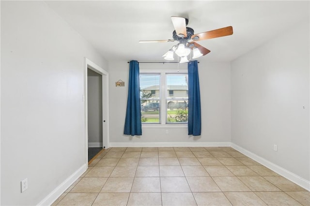 empty room with light tile patterned flooring, baseboards, and ceiling fan