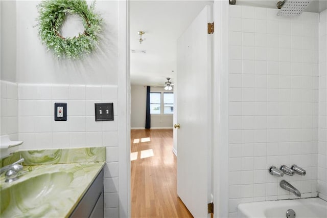 bathroom featuring vanity, wood finished floors, shower / bathing tub combination, ceiling fan, and tile walls